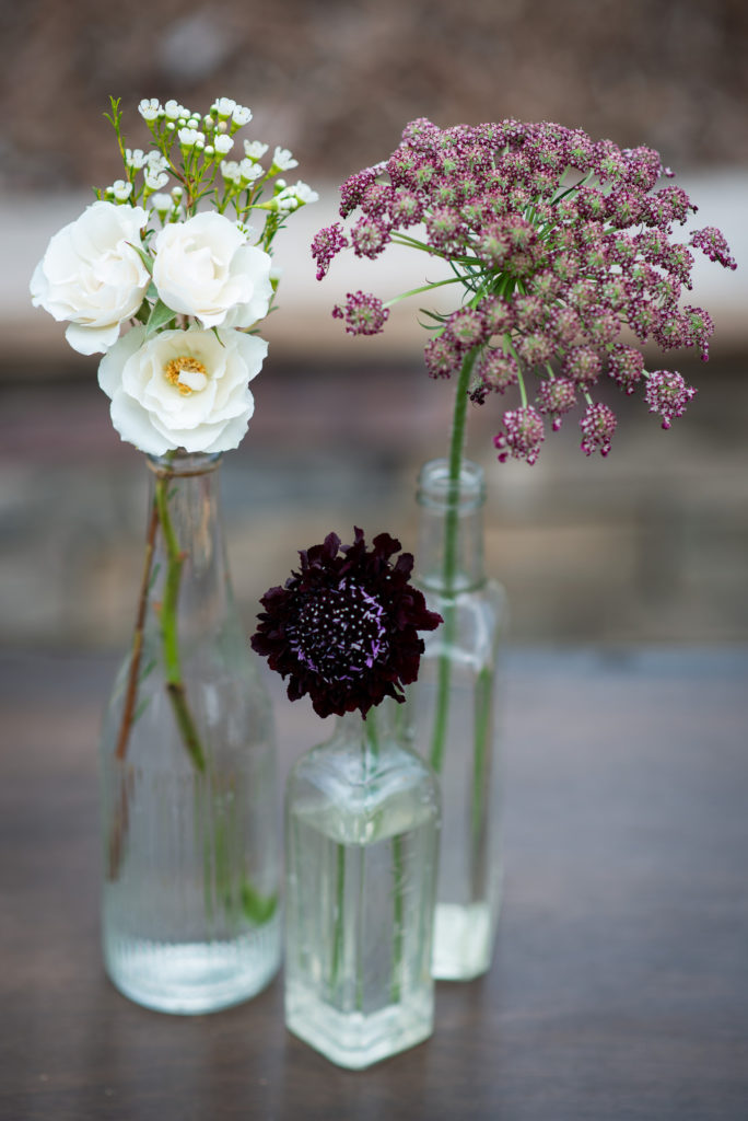 Simple centerpieces featuring vintage bottles and few flowers