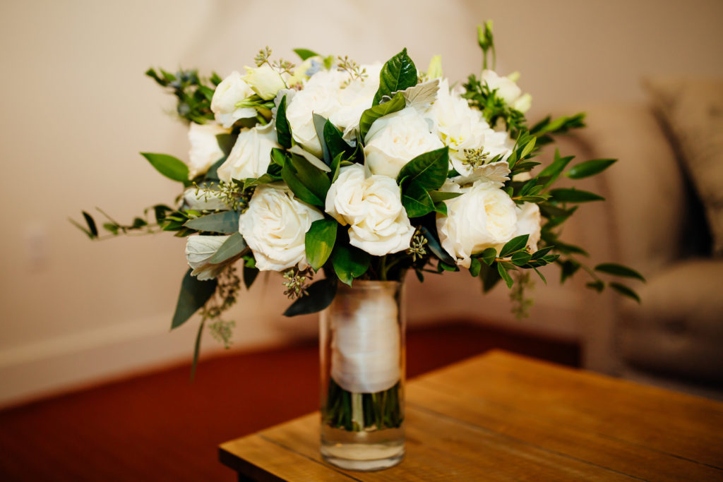 Bridal bouquet incorporating white roses and simple greenery.
